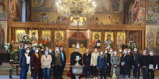 Studierende stehen in einer griechisch-orthodoxen Gemeinde hinter einem Taufbecken