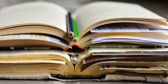 Bücher Aufgeschlagene Bücher und Stifte