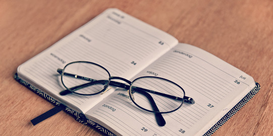 Offener Terminkalender auf dem eine Brille liegt