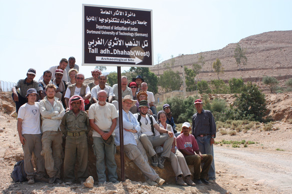 Archäologen und Ausgräber mit einem Schild zur Ausgrabungsstätte